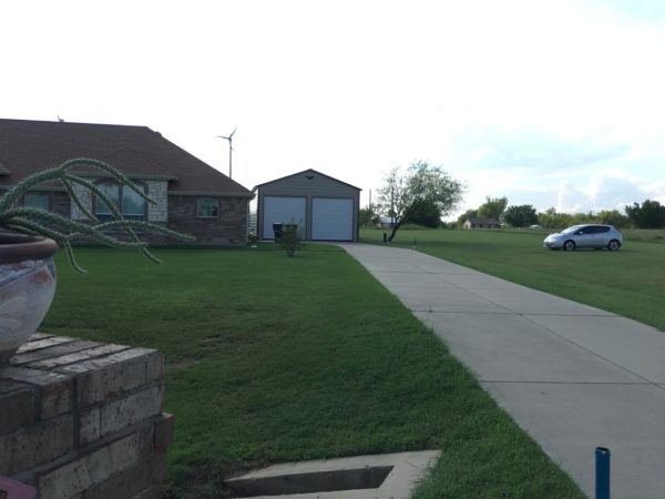 Picture of a driveway with double wide metal garage and garage doors.