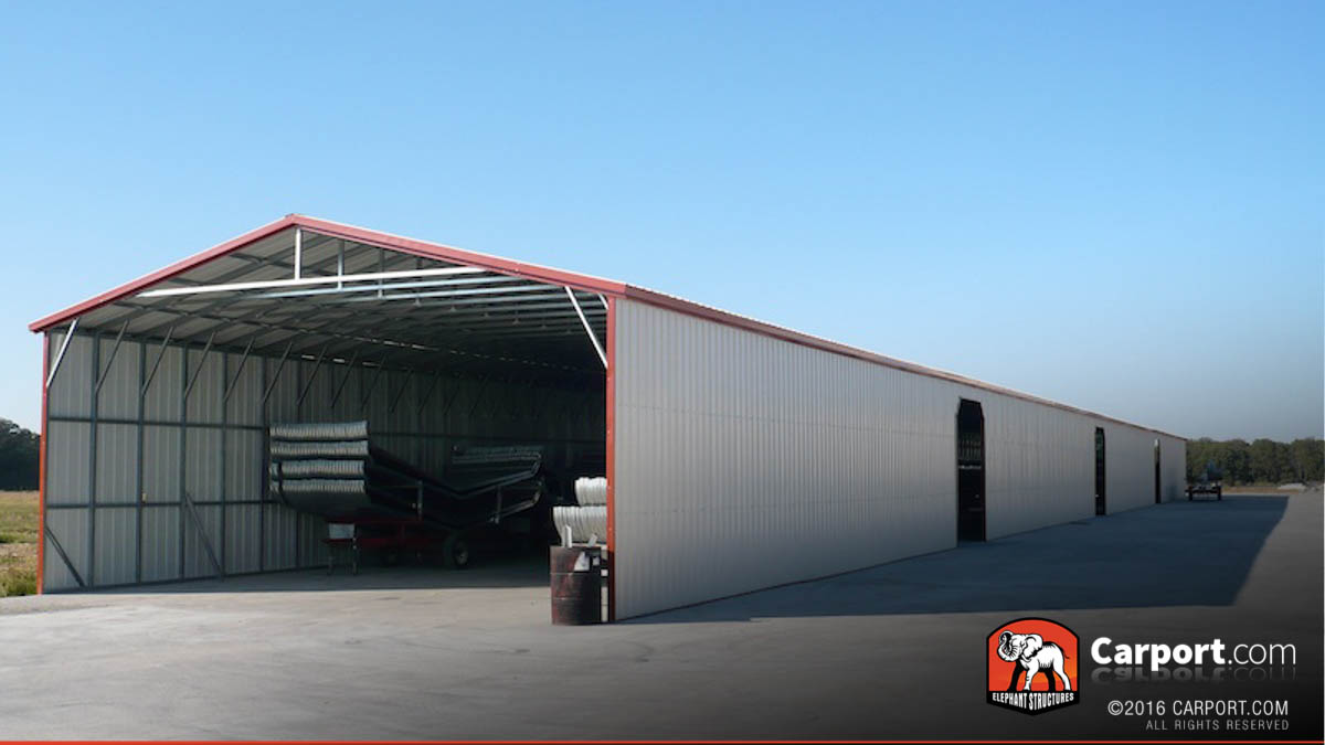 Commercial metal garage with roll up doors and trailors parked inside.