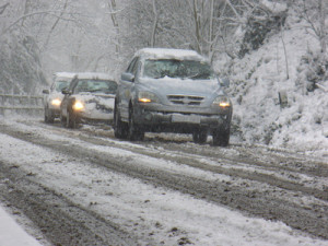 cars traveling slowly down a snow fallen road