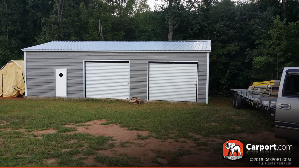 Commercial metal building with two roll up garage doors and one window.