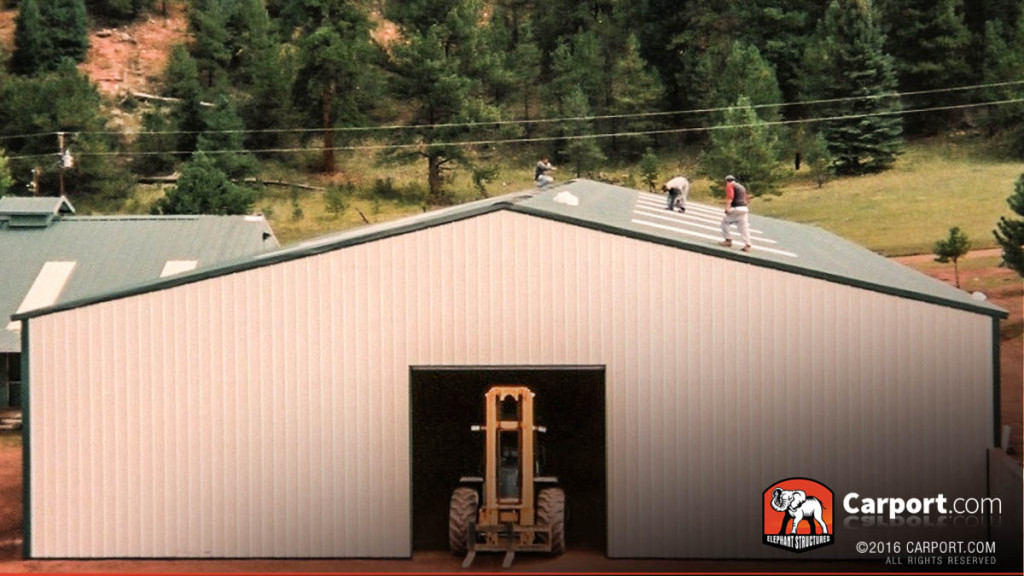 Large commercial metal building with one roll-up garage door and crew on top checking the lights.