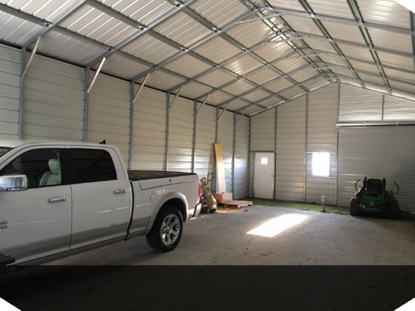Inside of a double wide garage building with three garage doors, a window, and a single man door with a truck parked inside.