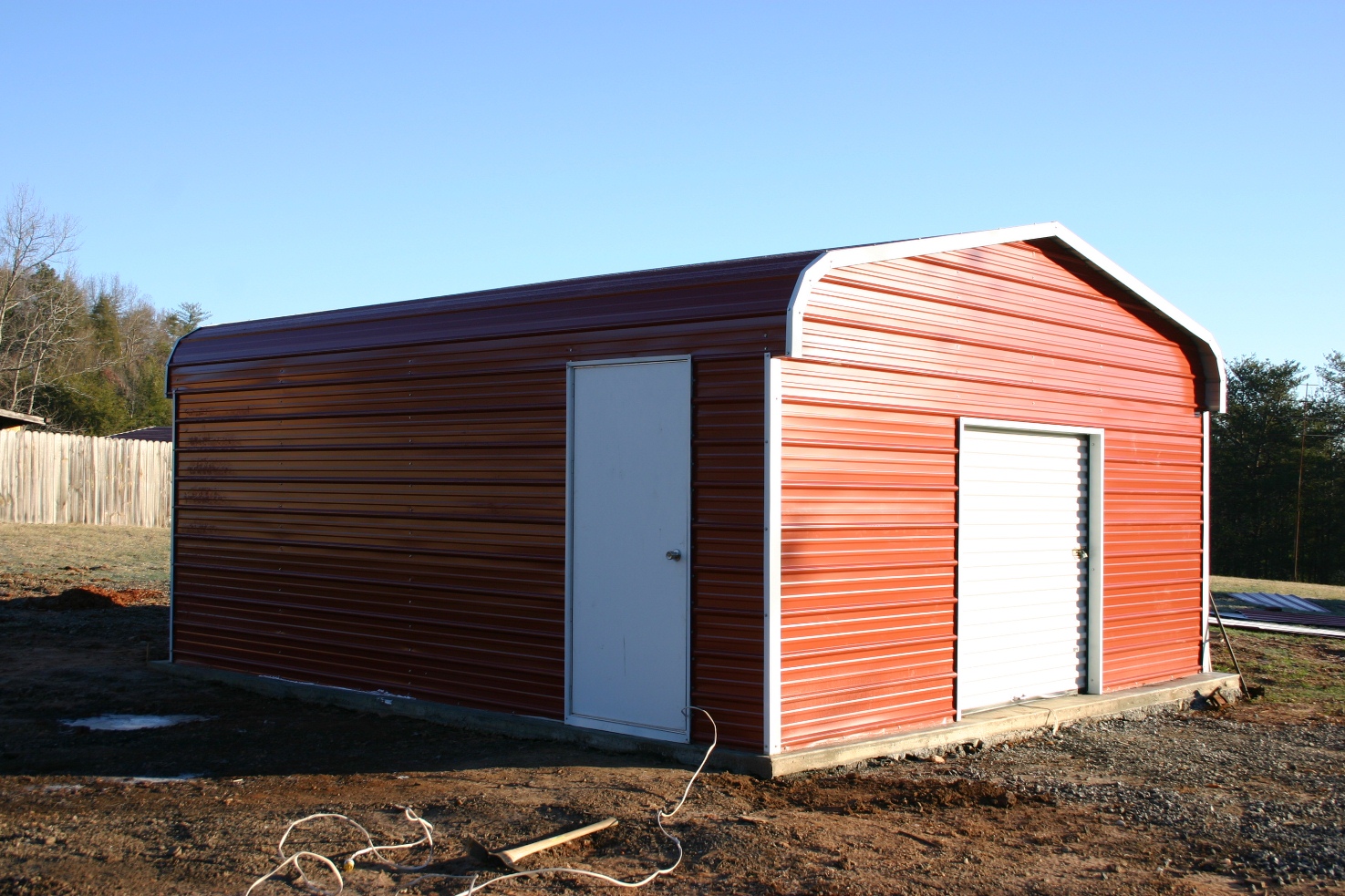 motorcycle-metal-garage Metal motorcycle garage with red walls and white roll-up garage door.
