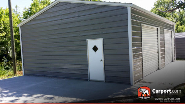 Two car metal garage building with two roll up garage doors and one man door.
